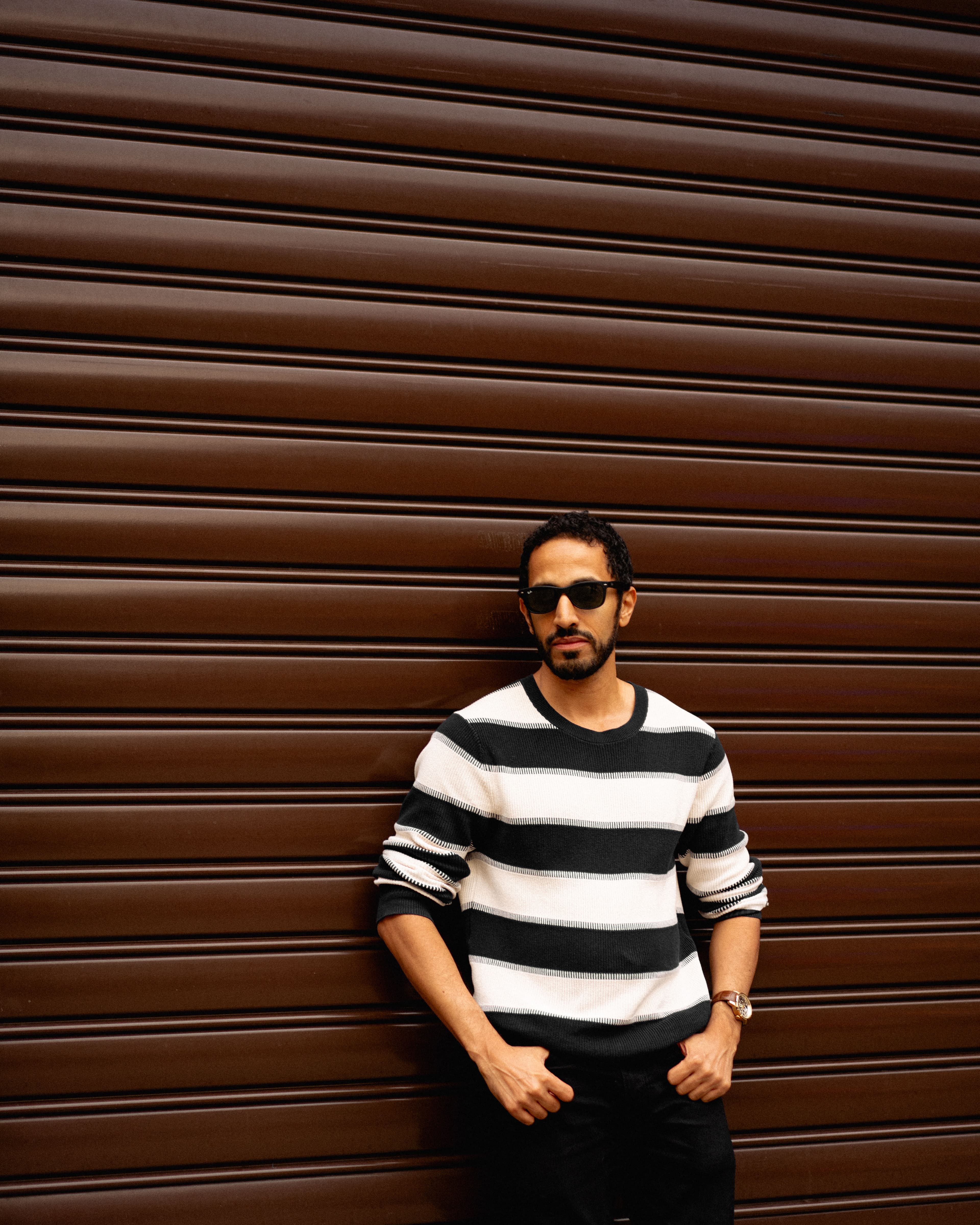 Stellar Dean wearing sunglasses in front of a warm brown cinematic wall